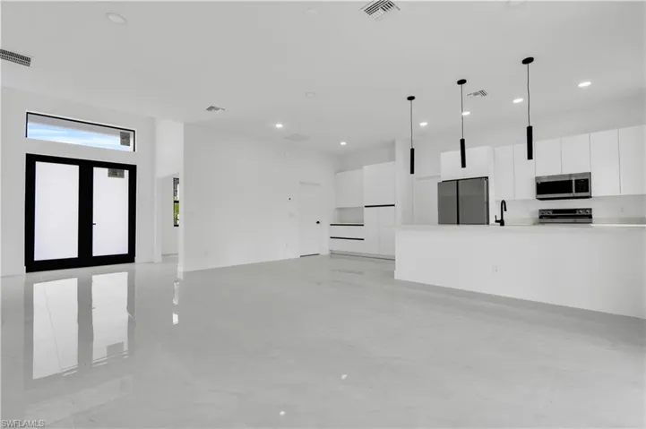 Unfurnished living room with recessed lighting, a sink, light marble finish flooring, and a towering ceiling