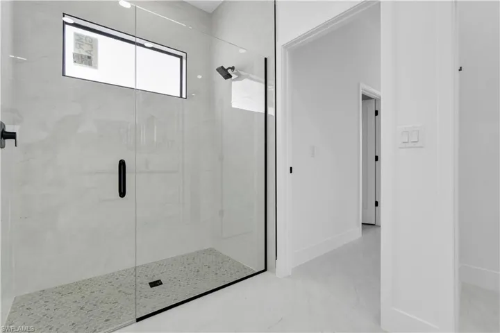 Full bathroom featuring a stall shower, baseboards, and marble finish floors
