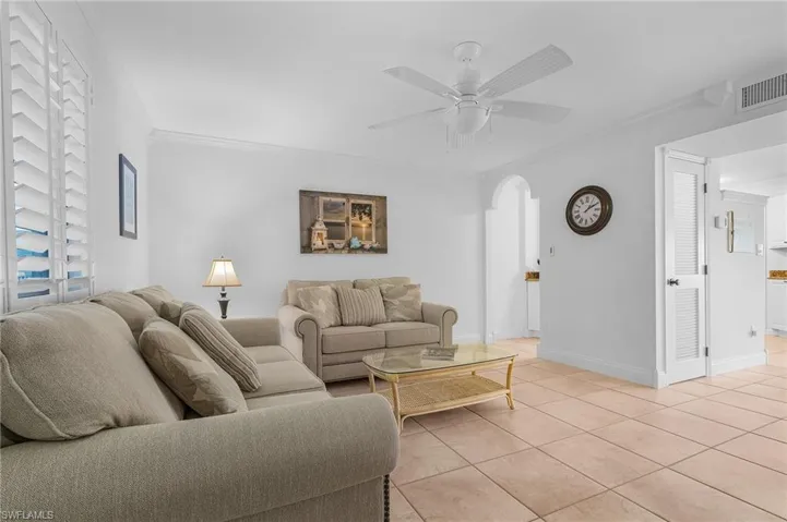 Living room with ornamental molding, ceiling fan, and light tile patterned floors