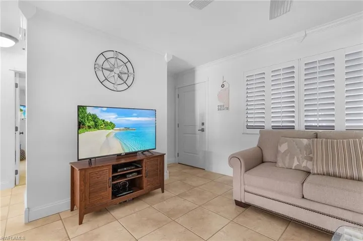 Tiled living room featuring crown molding