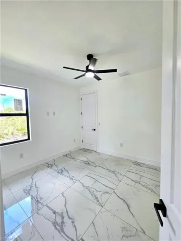 Empty room featuring ceiling fan and light tile patterned floors