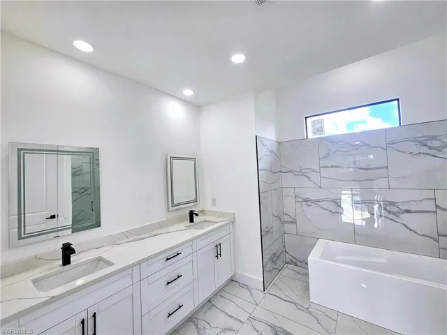 Bathroom featuring tile patterned flooring, vanity, and separate shower and tub