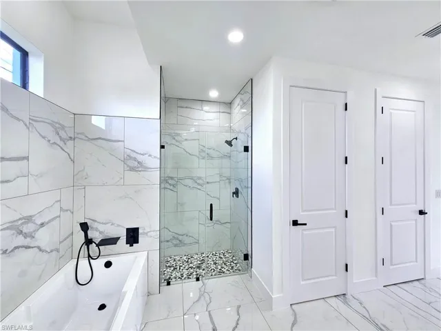 Bathroom with tile patterned flooring, shower with separate bathtub, and tile walls