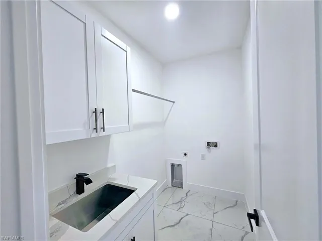 Laundry area featuring hookup for a washing machine, light tile patterned floors, electric dryer hookup, sink, and cabinets
