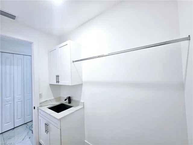 Laundry area featuring sink and light tile patterned flooring