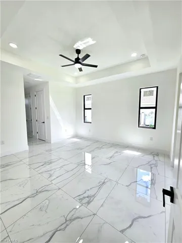 Tiled spare room with ceiling fan and a raised ceiling