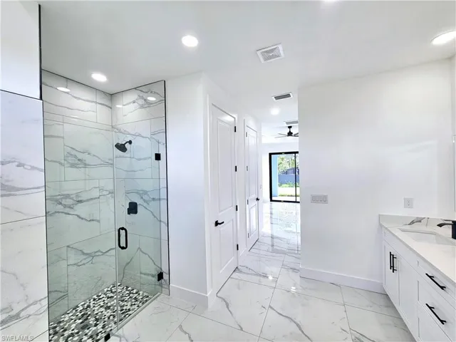 Bathroom featuring vanity, tile patterned flooring, ceiling fan, and a shower with door