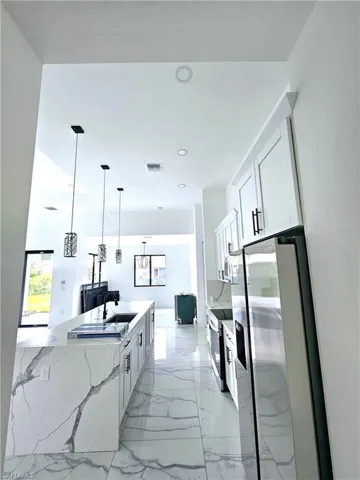 Kitchen featuring pendant lighting, sink, white cabinetry, white electric stove, and light tile patterned flooring