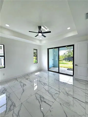 Tiled empty room featuring a raised ceiling and ceiling fan