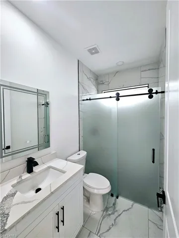 Bathroom with tile patterned flooring, walk in shower, toilet, and vanity