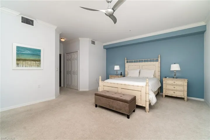 Carpeted bedroom with ceiling fan, a closet, and ornamental molding