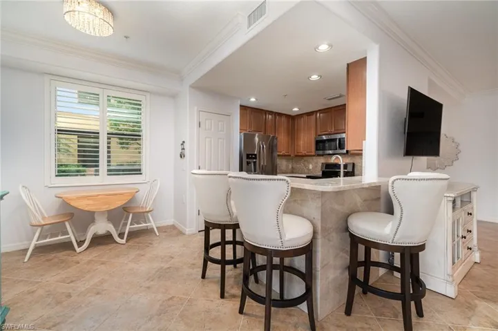 Kitchen featuring stainless steel appliances, a kitchen breakfast bar, backsplash, and crown molding