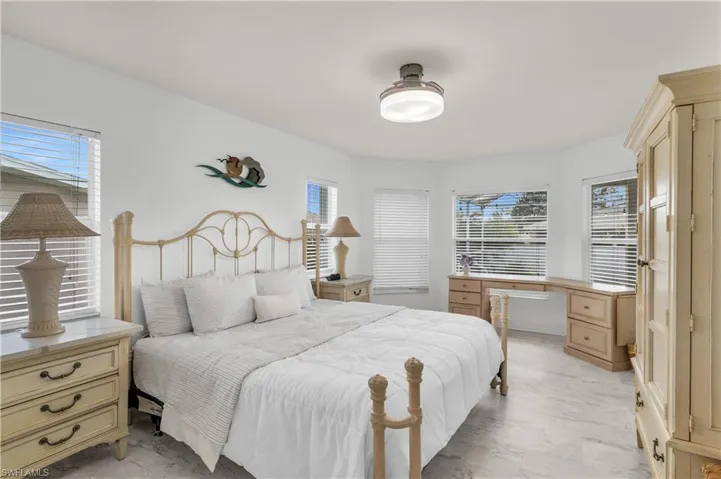 Bedroom with light marble finish floors, multiple windows, and a ceiling fan