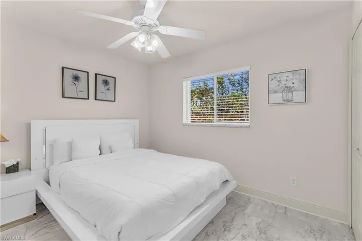 Bedroom with ceiling fan and light marble finish floors