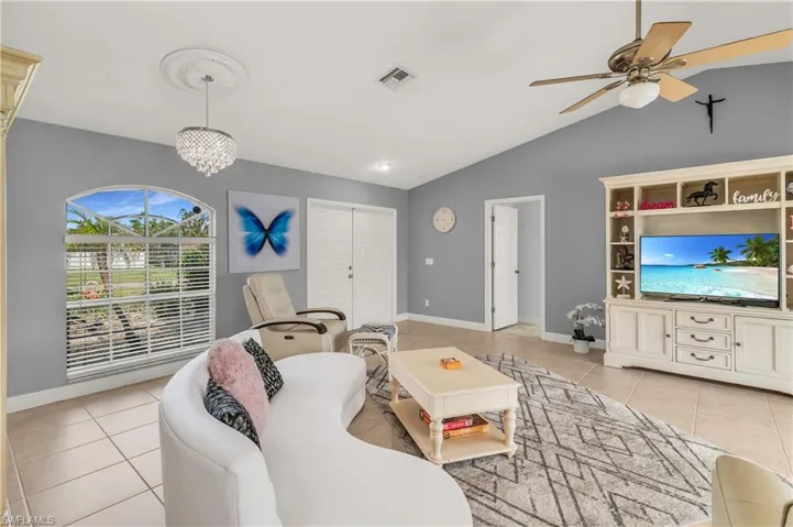 Living room with light tile patterned floors, suspended lighting, ceiling fan, and vaulted ceiling