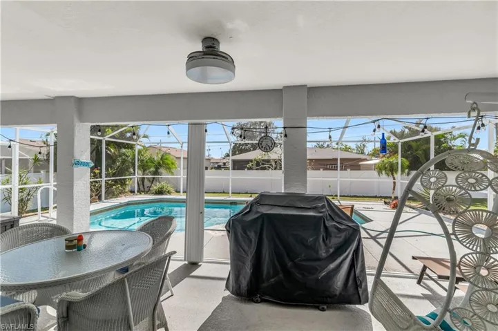 View of swimming pool with glass enclosure, a sunroom, grilling area, patio surround, and outdoor dining space