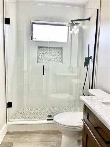 Bathroom featuring walk in shower, vanity, toilet, and hardwood / wood-style floors