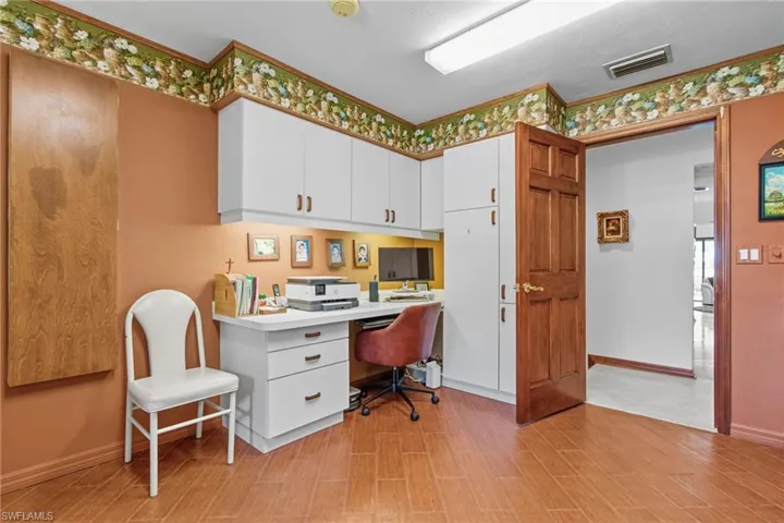Office area featuring light wood-style floors and built in study area