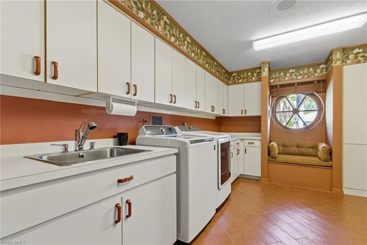 Laundry room featuring light wood-type flooring, cabinet space, and washing machine and dryer