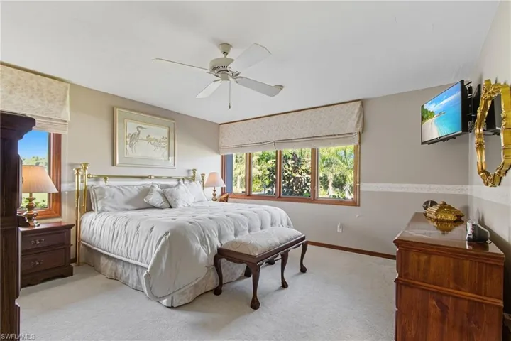 Bedroom featuring multiple windows, carpet, and ceiling fan.