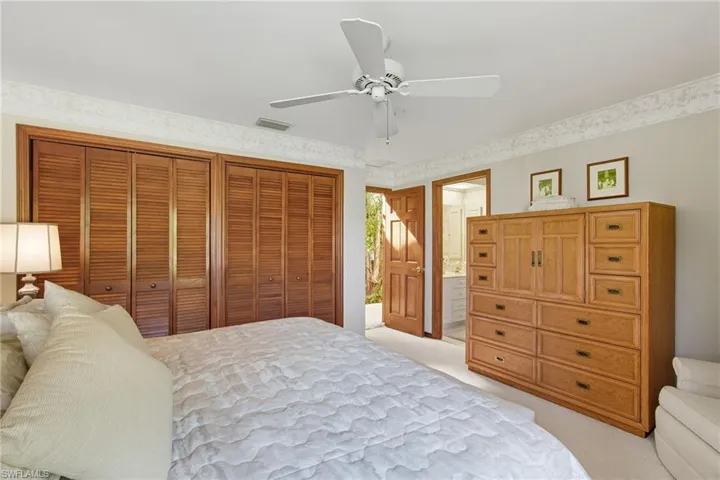 Bedroom with light carpet, multiple closets, a ceiling fan, and ensuite bathroom