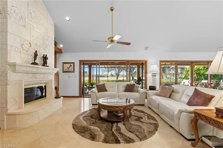 Great room with high vaulted ceiling, a premium fireplace, a ceiling fan, tile floors, and sliders out to the lanai.