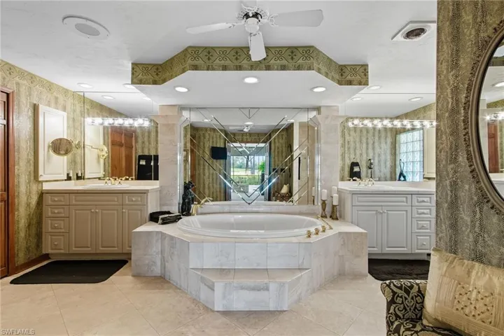 Full bath featuring two vanities, a garden tub, light tile floors, a ceiling fan, and recessed lighting.