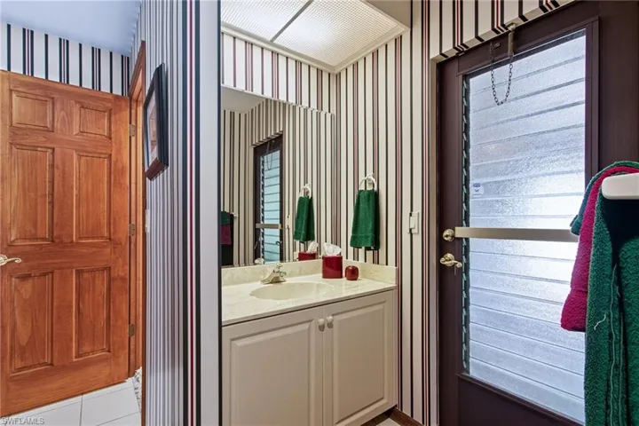 Bathroom featuring vanity, tile patterned flooring, and wallpapered walls