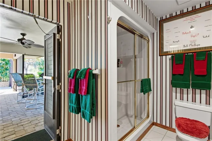Full bathroom with a stall shower, wallpapered walls, and ceiling fan