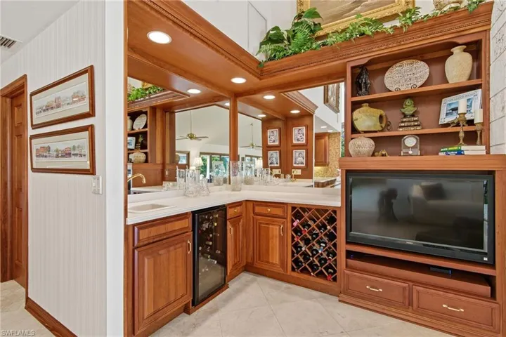 Great room wet bar featuring mirrored wall, cabinet space, tile flooring, wine storage and wine cooler.