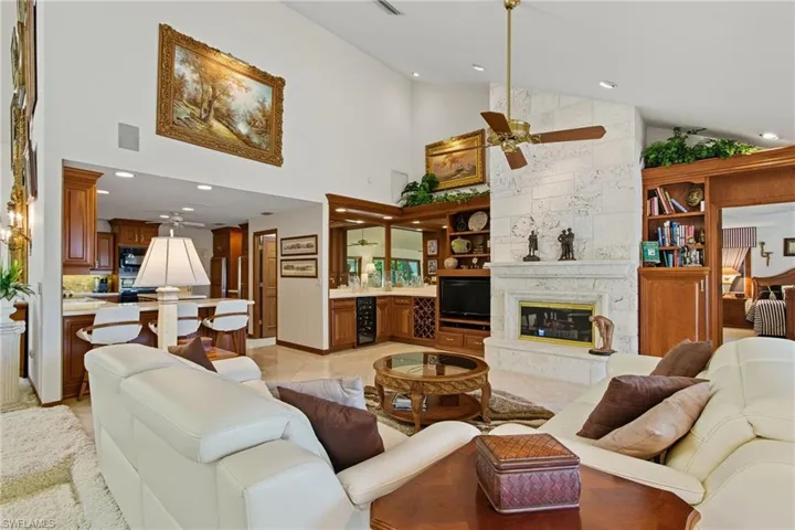 Living area featuring high vaulted ceiling, recessed lighting, ceiling fan, tile floors and wet bar with wine cooler.