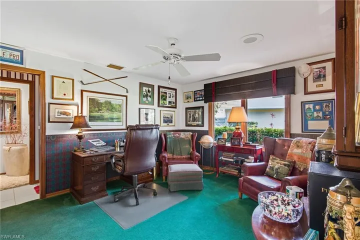 Home office with a wainscoted wall, carpet floors, and ceiling fan