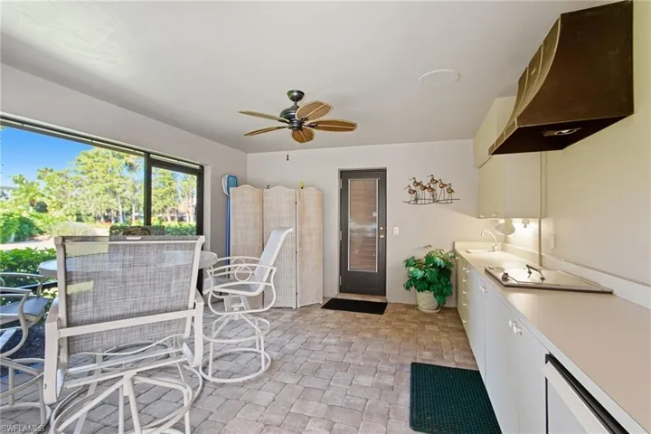 Outdoor kitchen area with paver deck, sink, beverage refrigerator, pool bath.