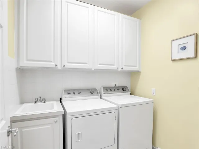 Laundry room featuring independent washer and dryer, cabinets, and sink
