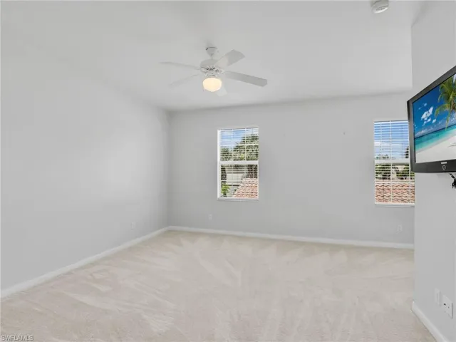 Carpeted spare room featuring plenty of natural light and ceiling fan