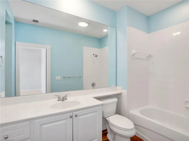 Full bathroom featuring hardwood / wood-style floors, tiled shower / bath, toilet, and vanity