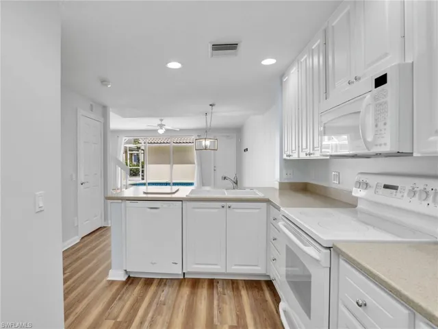 Kitchen with light hardwood / wood-style flooring, white appliances, sink, kitchen peninsula, and ceiling fan
