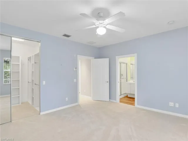Unfurnished bedroom with light colored carpet, connected bathroom, and a closet