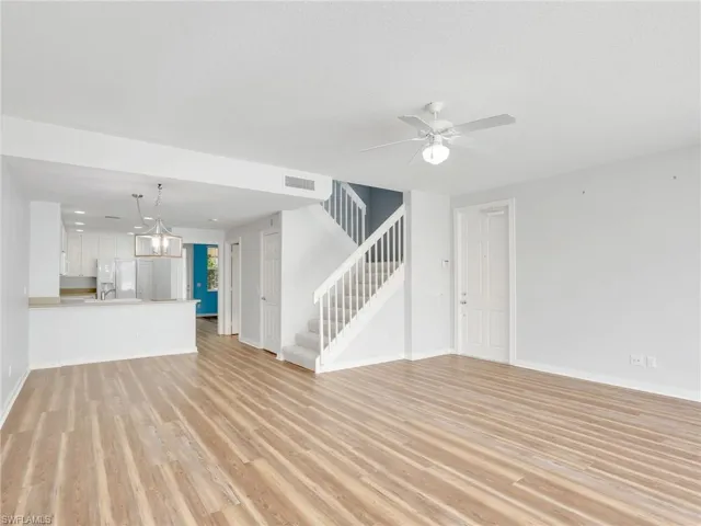 Unfurnished living room with hardwood / wood-style floors, ceiling fan with notable chandelier, and a textured ceiling