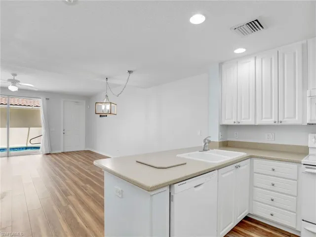 Kitchen with light hardwood / wood-style flooring, white appliances, sink, kitchen peninsula, and ceiling fan
