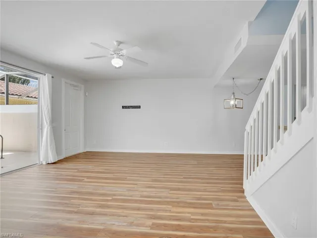 Spare room with ceiling fan with notable chandelier and light hardwood / wood-style flooring