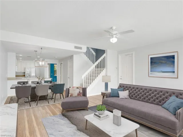 Living room with light wood-type flooring and ceiling fan with notable chandelier