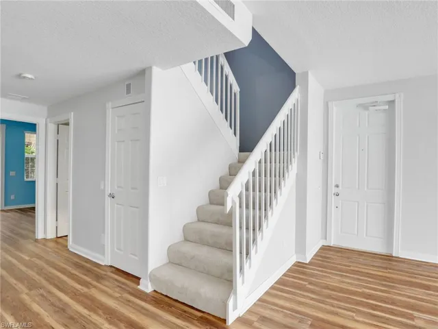 Staircase featuring a textured ceiling and wood-type flooring