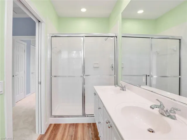 Bathroom featuring a shower with shower door and vanity