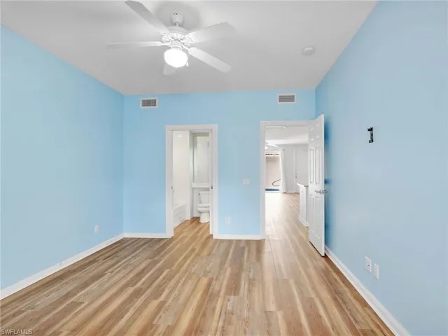 Unfurnished bedroom featuring light wood-type flooring, ceiling fan, and ensuite bath