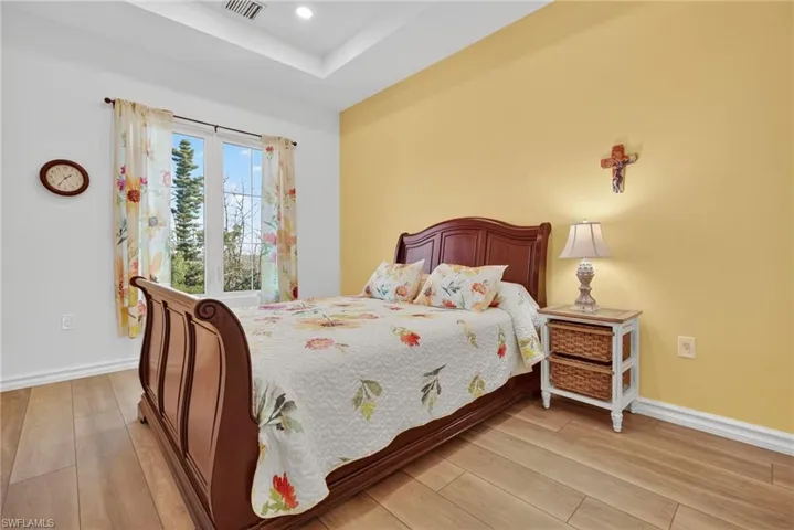 Bedroom featuring light wood-type flooring, a raised ceiling, and recessed lighting