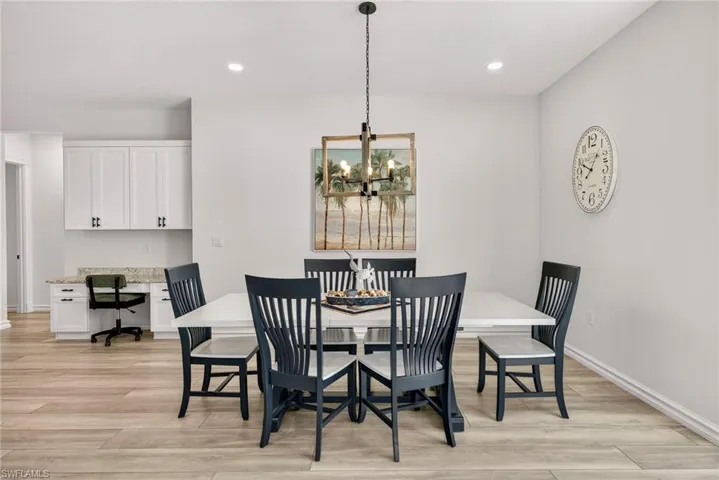 Dining room with light wood-type flooring, recessed lighting, a chandelier, and built in study area