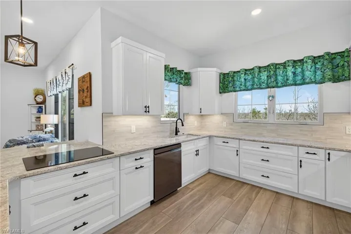 Kitchen with recessed lighting, white cabinets, light stone countertops, light wood-style floors, and stainless steel dishwasher