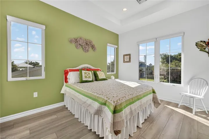 Bedroom with wood finished floors, recessed lighting, and a raised ceiling