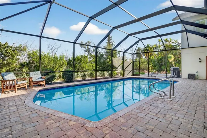 Outdoor pool featuring a sunroom, glass enclosure, and a patio area